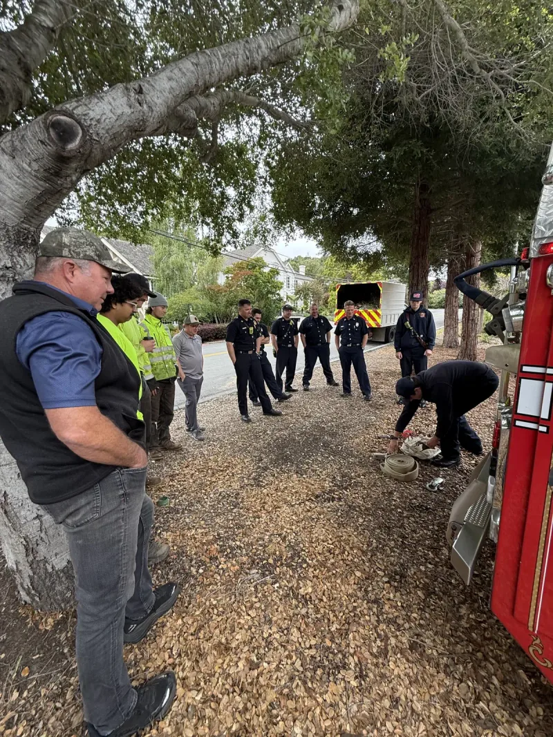 Crew practicing recovery drills beside a fire engine at a training site.