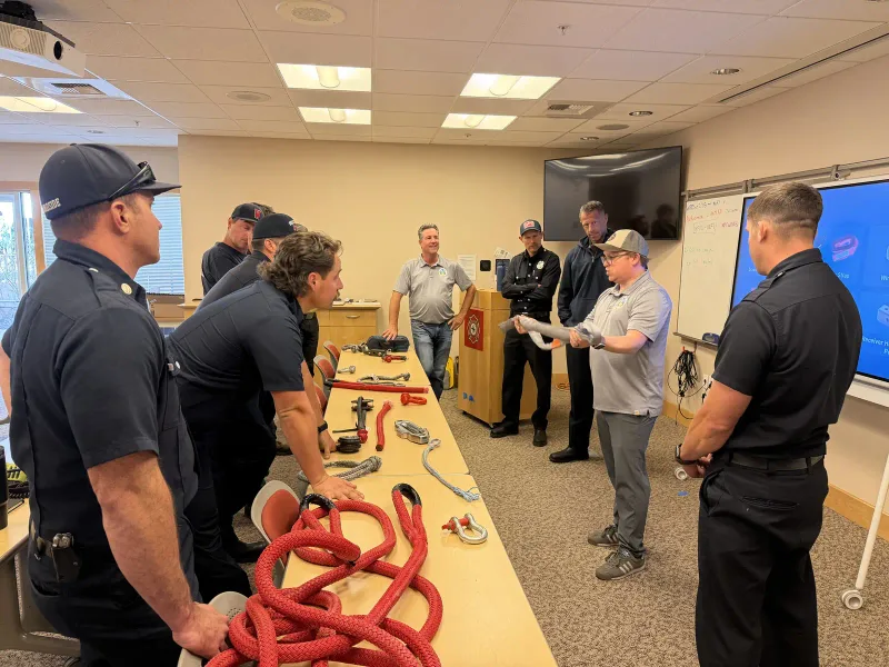 Instructor walking a class through recovery rigging and kinetic rope on a demo table.